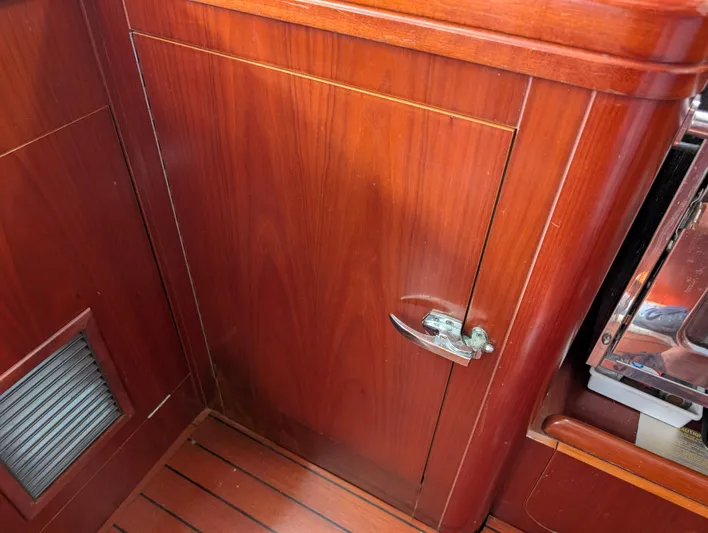 Seastar Yacht Photos Pics Wooden interior of 2003 Beneteau Oceanis 473 sailboat, featuring a cabinet with a metal latch.