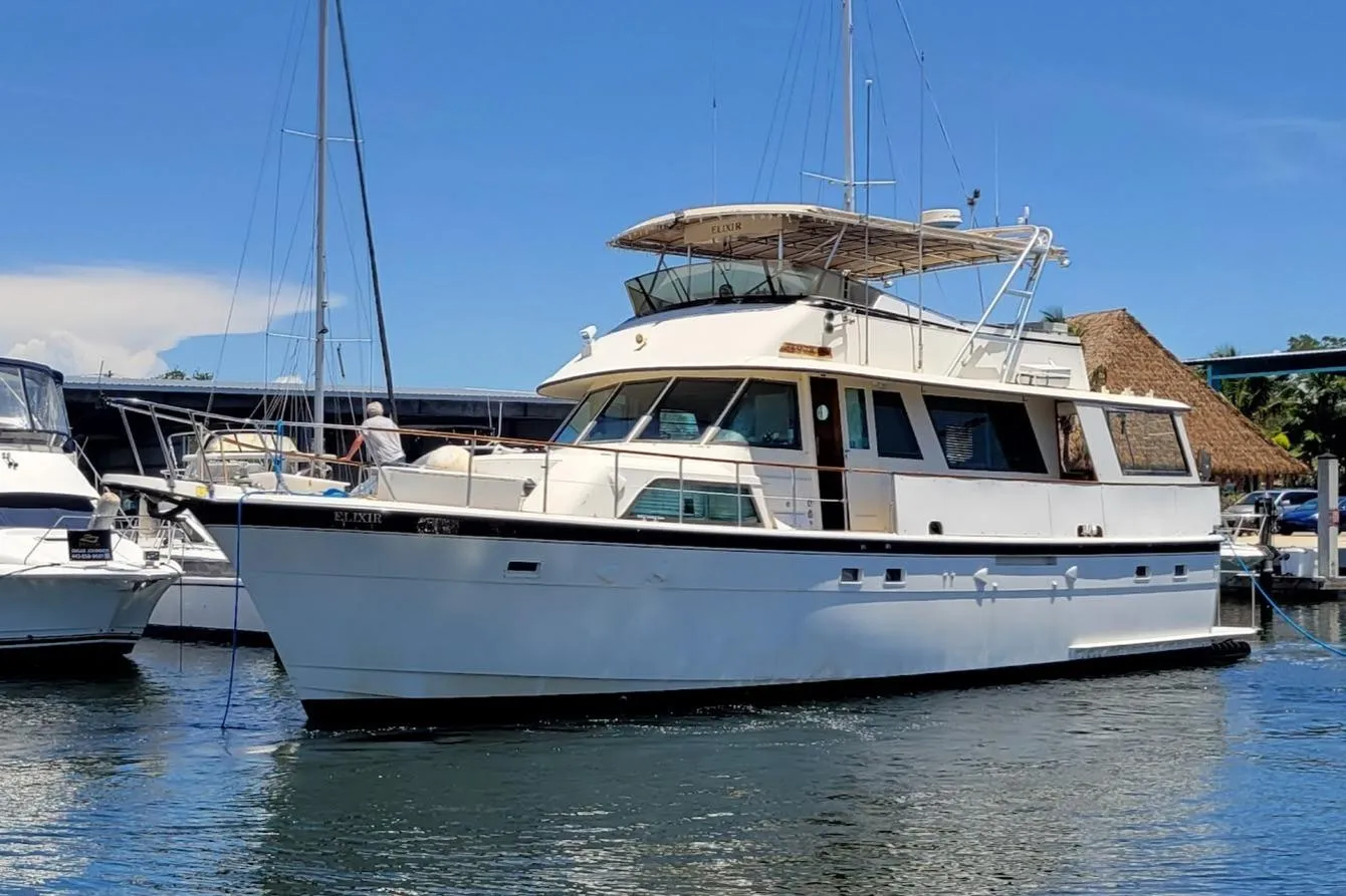 1982 Hatteras 56 Wide Body yacht docked in a marina under clear blue skies.