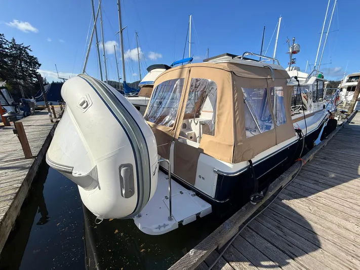 Salty Growler Yacht Photos Pics 2017 Ranger Tugs R-29 S docked, featuring tan canopy and attached dinghy.