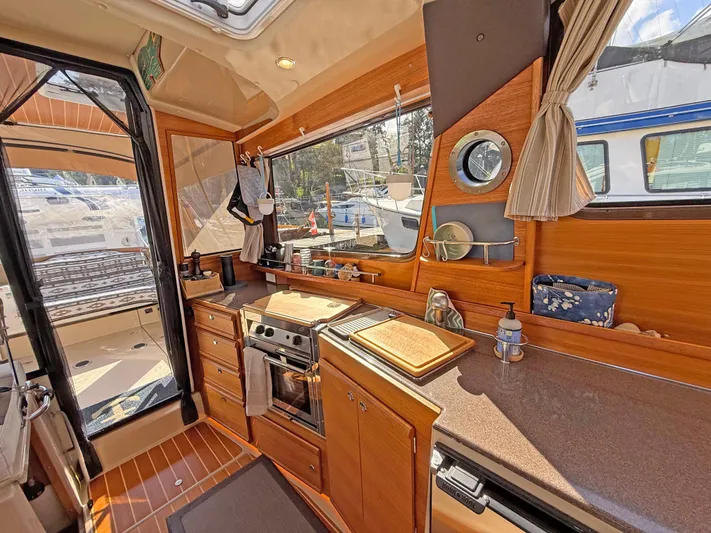 Salty Growler Yacht Photos Pics Interior of 2017 Ranger Tugs R-29 S, featuring a compact kitchen with wood cabinetry.