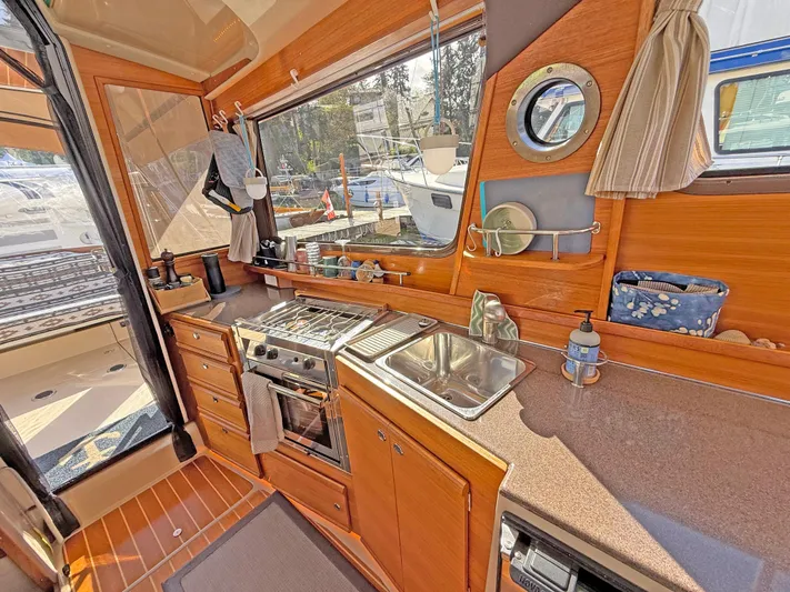 Salty Growler Yacht Photos Pics 2017 Ranger Tugs R-29 S galley with stove, sink, and wooden cabinetry.