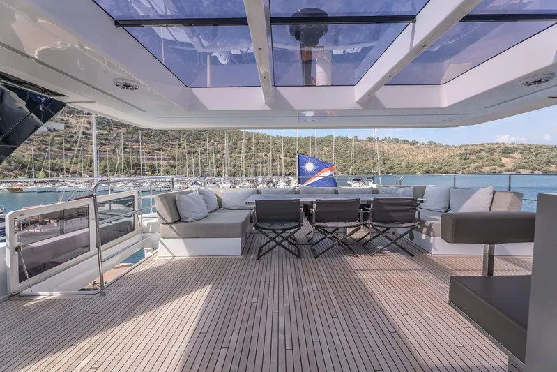  Yacht Photos Pics Luxurious Sunreef 60 Power yacht deck with seating, 2023 model, overlooking marina and hills.