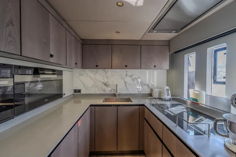  Yacht Photos Pics Modern kitchen interior on 2023 Sunreef 60 Power yacht, featuring sleek cabinetry and marble backsplash.