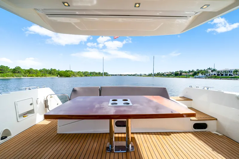 Our Trade Yacht Photos Pics Luxury 2017 Prestige 560 yacht deck with wooden table, scenic waterfront view.