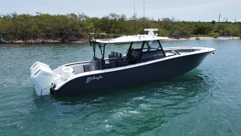  Yacht Photos Pics 2023 Yellowfin 42 boat on water near lush shoreline.