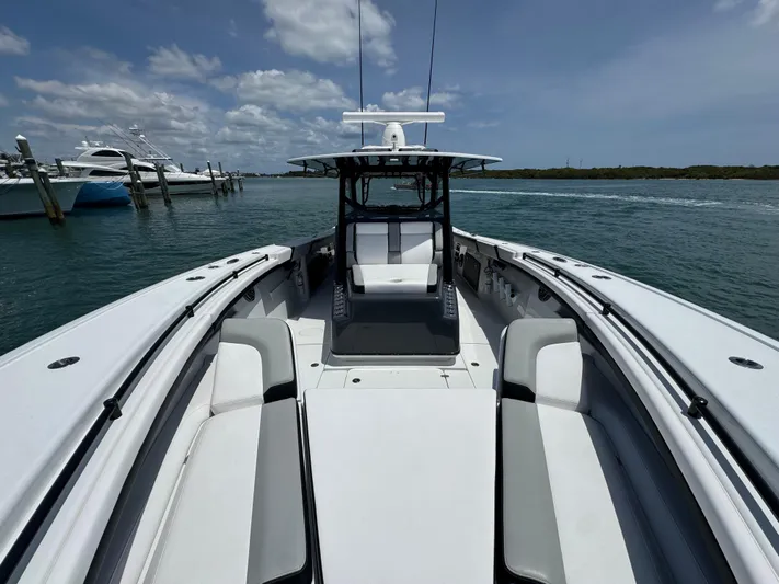  Yacht Photos Pics 2023 Yellowfin 42 boat on water, clear sky, docked yachts in background.