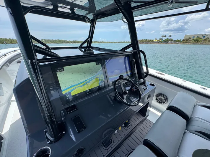  Yacht Photos Pics 2023 Yellowfin 42 boat cockpit with navigation screens and steering wheel, near scenic waterway.