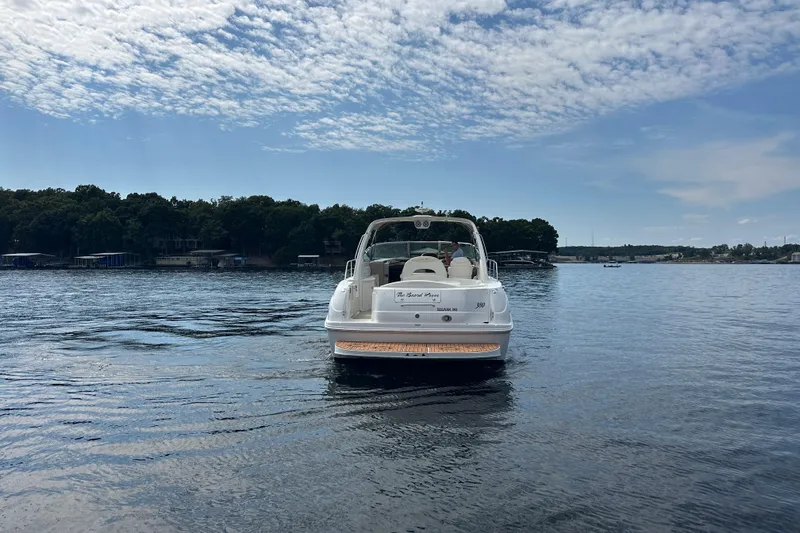  Yacht Photos Pics 2004 Sea Ray 380 Sundancer on a serene lake under a partly cloudy sky.