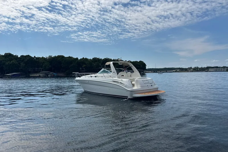  Yacht Photos Pics 2004 Sea Ray 380 Sundancer yacht cruising on a serene lake under a partly cloudy sky.