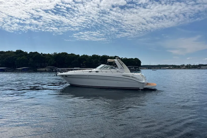  Yacht Photos Pics 2004 Sea Ray 380 Sundancer yacht on a calm lake under a partly cloudy sky.