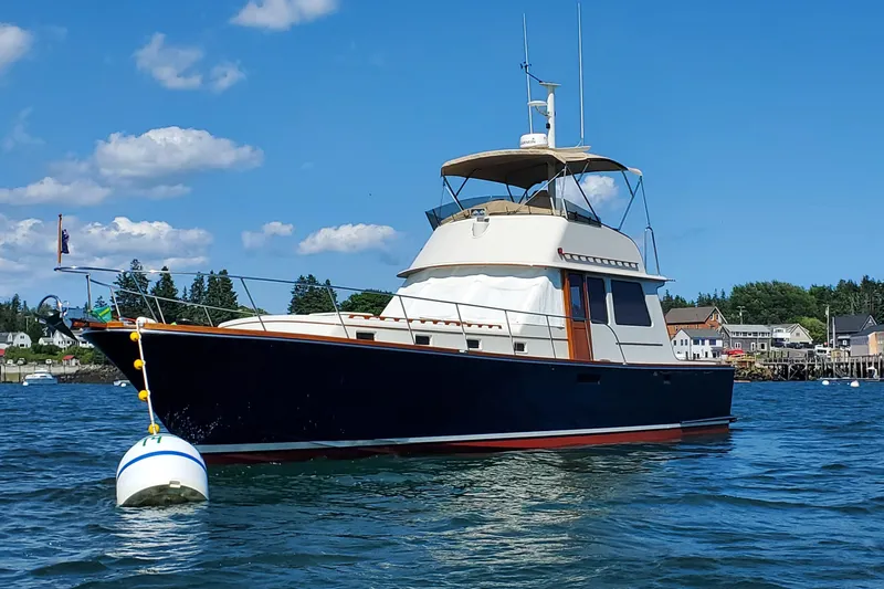 Minkie B Yacht Photos Pics 1997 Lyman-Morse Custom Flybridge yacht on calm water, clear blue sky background.