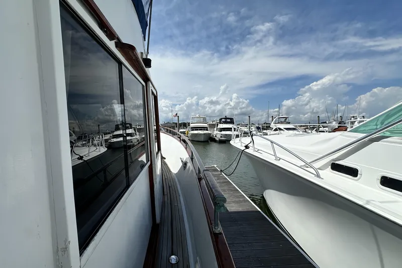 Maren Yacht Photos Pics 1980 Island Gypsy Flush Aft Deck Trawler-Motor Yacht docked at marina under blue sky.