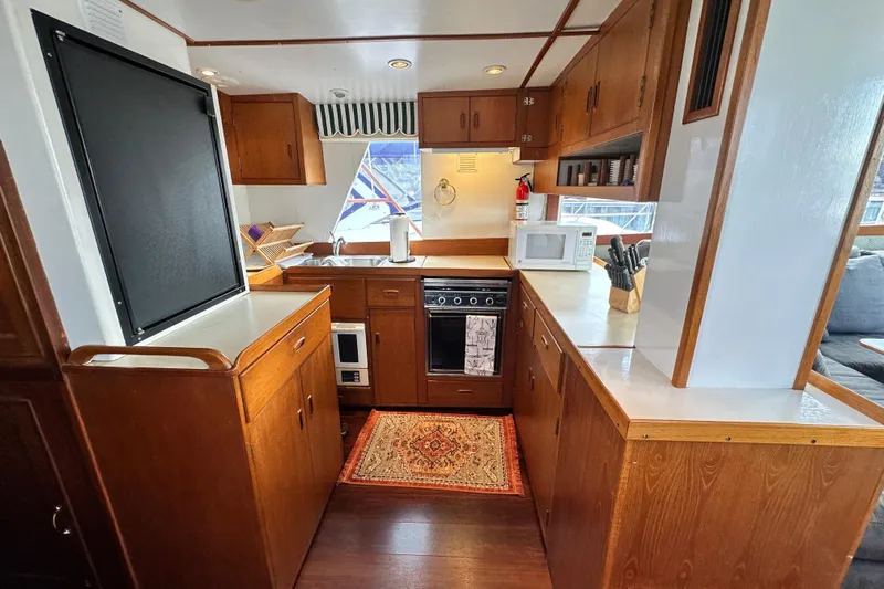 Maren Yacht Photos Pics 1980 Island Gypsy yacht kitchen with wood cabinetry, stove, microwave, and sink.