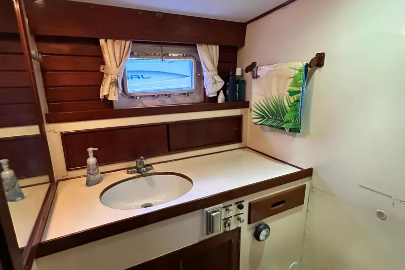 Maren Yacht Photos Pics 1980 Island Gypsy yacht bathroom with wooden accents, sink, and tropical-themed towel.