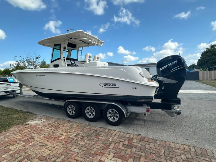  Yacht Photos Pics 2013 Boston Whaler 320 Outrage boat on trailer, parked outdoors under blue sky.