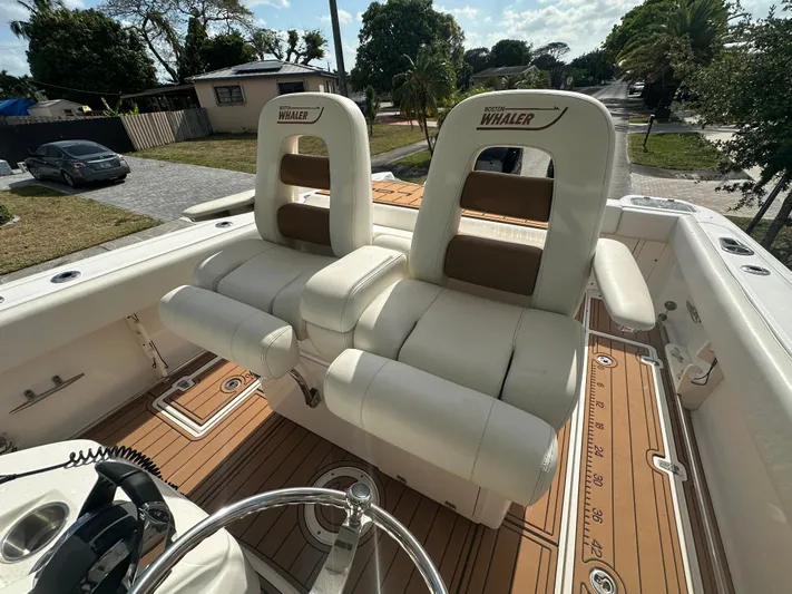  Yacht Photos Pics 2013 Boston Whaler 320 Outrage boat interior with dual white captain's chairs and teak flooring.