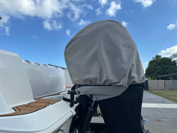  Yacht Photos Pics 2013 Boston Whaler 320 Outrage boat with covered outboard motor, under a clear blue sky.