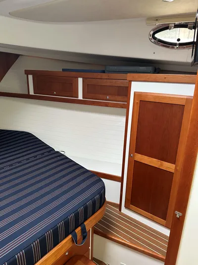 Waters Edge Yacht Photos Pics 2018 Back Cove Downeast 37 cabin interior with striped bedding and wooden cabinetry.