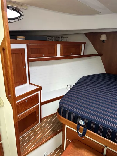 Waters Edge Yacht Photos Pics 2018 Back Cove Downeast 37 cabin interior with wood cabinetry and striped bedding.
