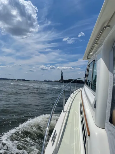 Waters Edge Yacht Photos Pics 2018 Back Cove Downeast 37 cruising near the Statue of Liberty under a blue sky.