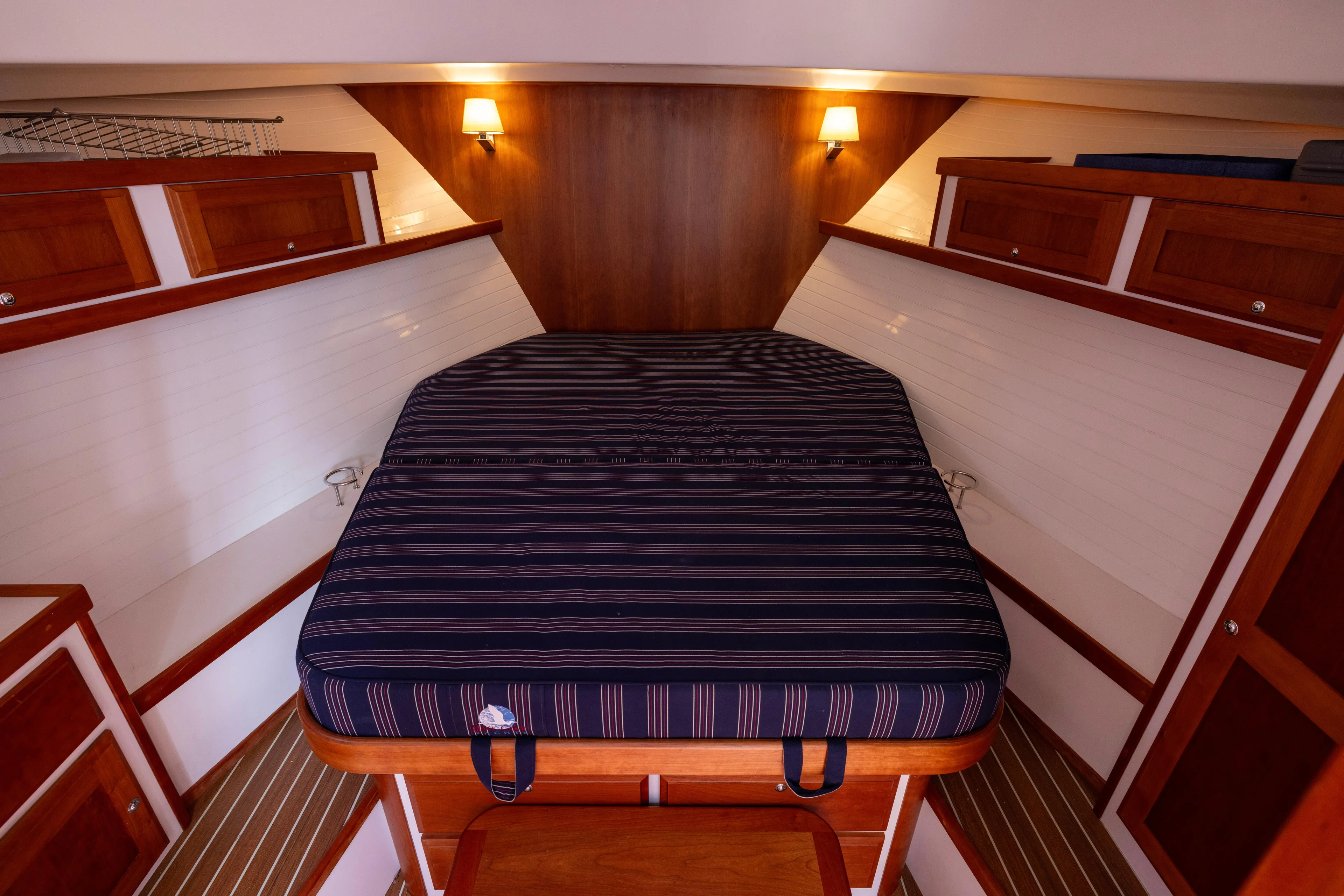 Waters Edge Yacht Photos Pics 2018 Back Cove Downeast 37 cabin interior with striped bedding and wooden cabinetry.