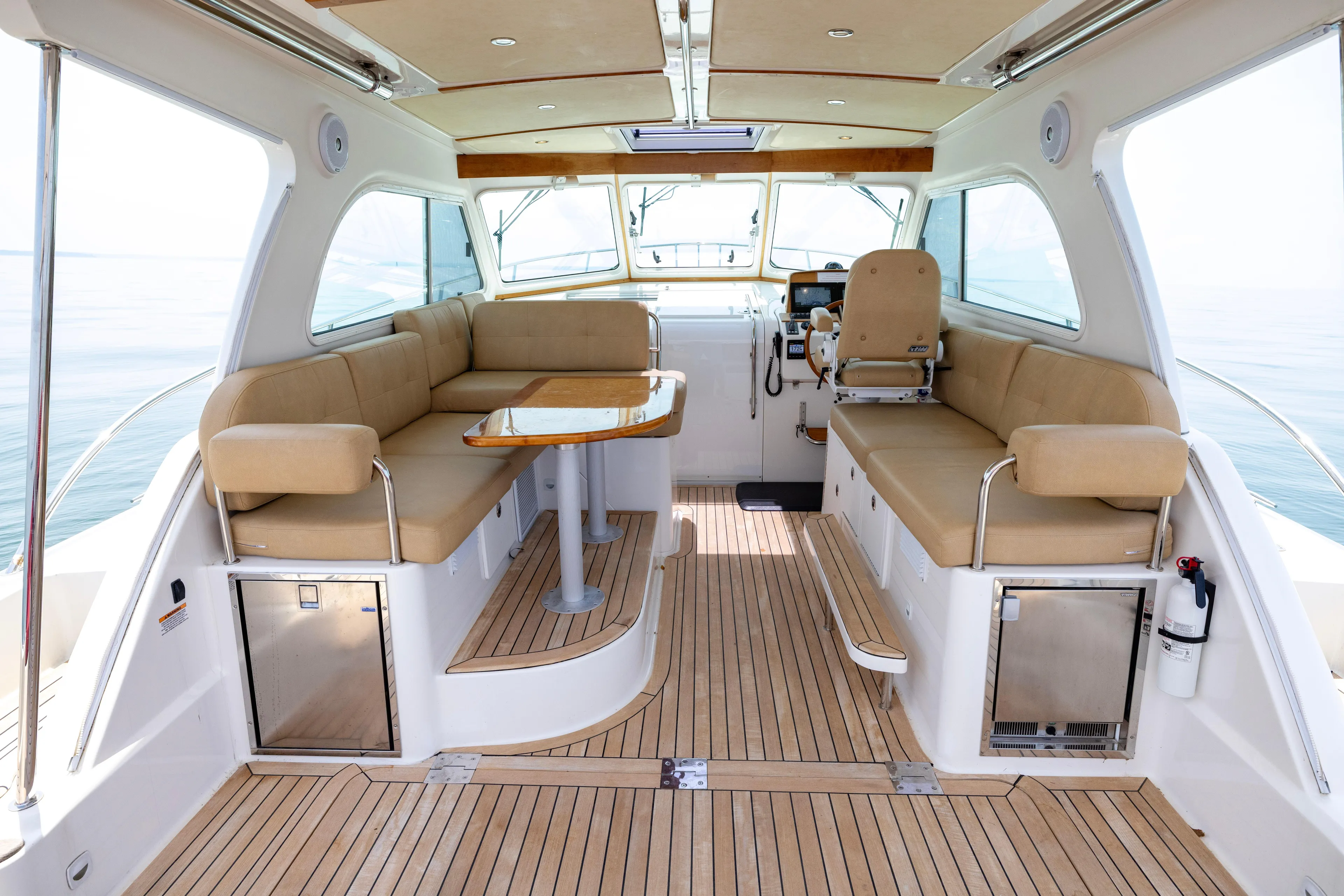 Waters Edge Yacht Photos Pics 2018 Back Cove Downeast 37 interior with beige seating, wooden flooring, and helm station.