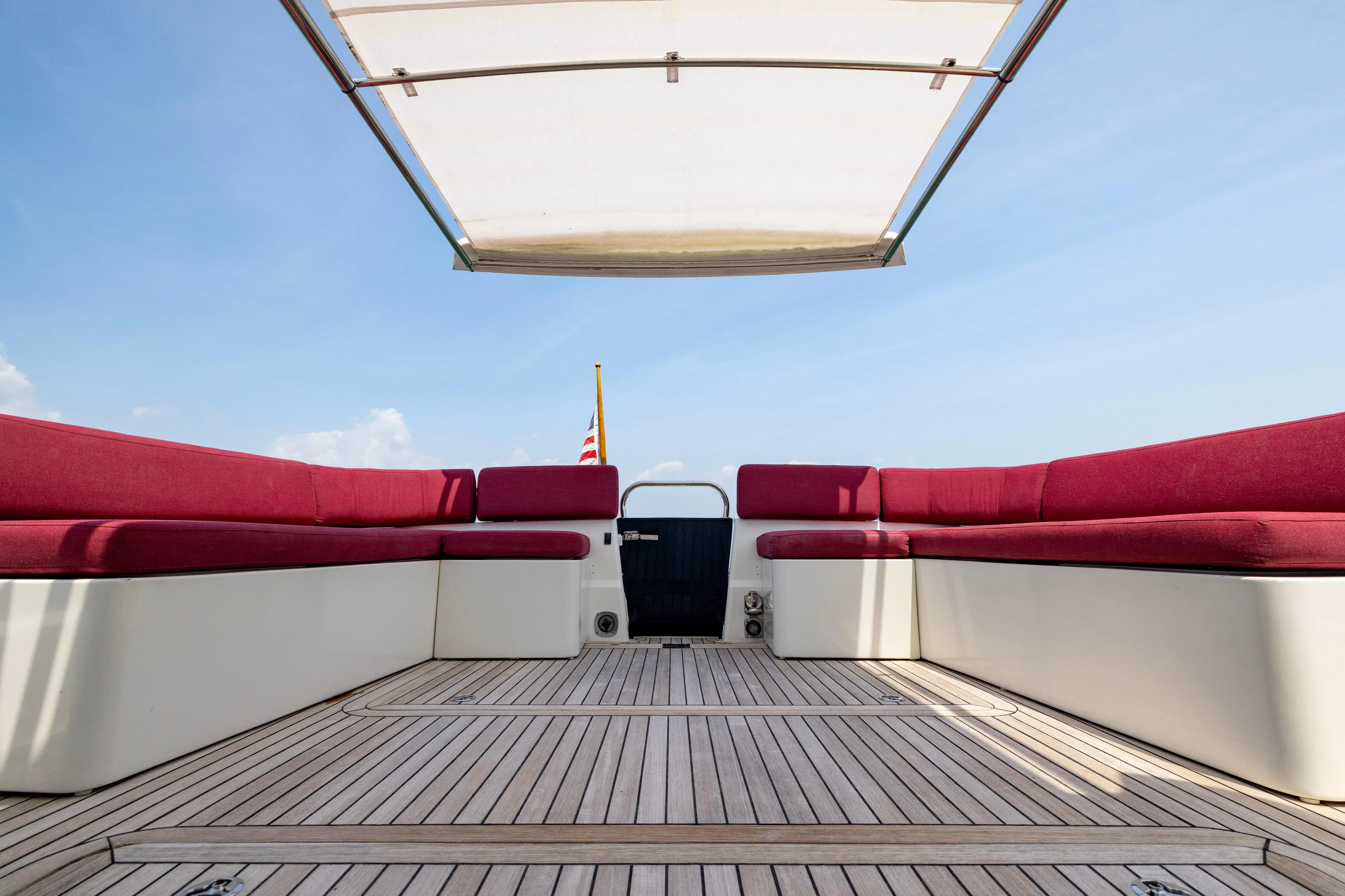 Waters Edge Yacht Photos Pics 2018 Back Cove Downeast 37 boat deck with red seating and canopy under blue sky.