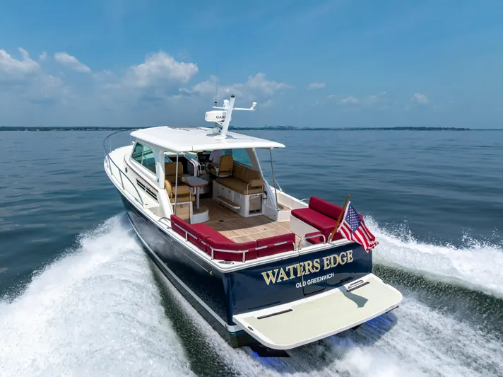 Waters Edge Yacht Photos Pics 2018 Back Cove Downeast 37 cruising on open water, rear view with American flag.