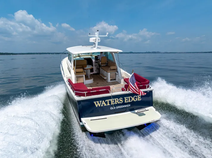 Waters Edge Yacht Photos Pics 2018 Back Cove Downeast 37 cruising on open water, rear view with American flag.
