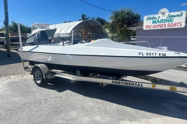 White JJM VS 1985 boat on trailer at marine dealership, sunny day.