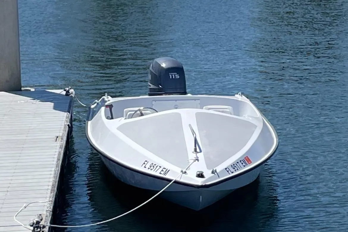 1985 JJM VS boat docked on calm water with outboard motor.