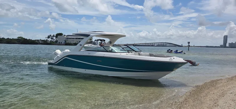  Yacht Photos Pics 2021 Sea Ray SLX 310 Outboard boat on calm waters near a sandy shore.