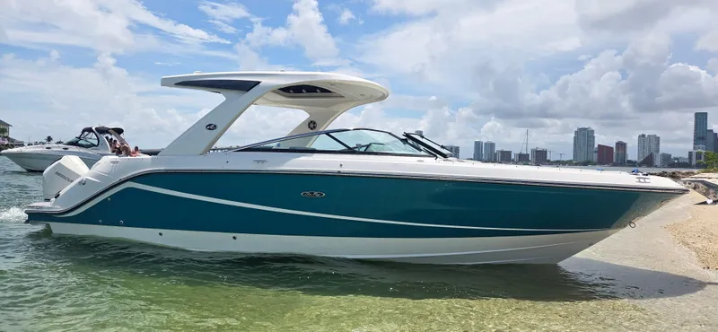  Yacht Photos Pics 2021 Sea Ray SLX 310 Outboard boat on a sunny beach with city skyline.
