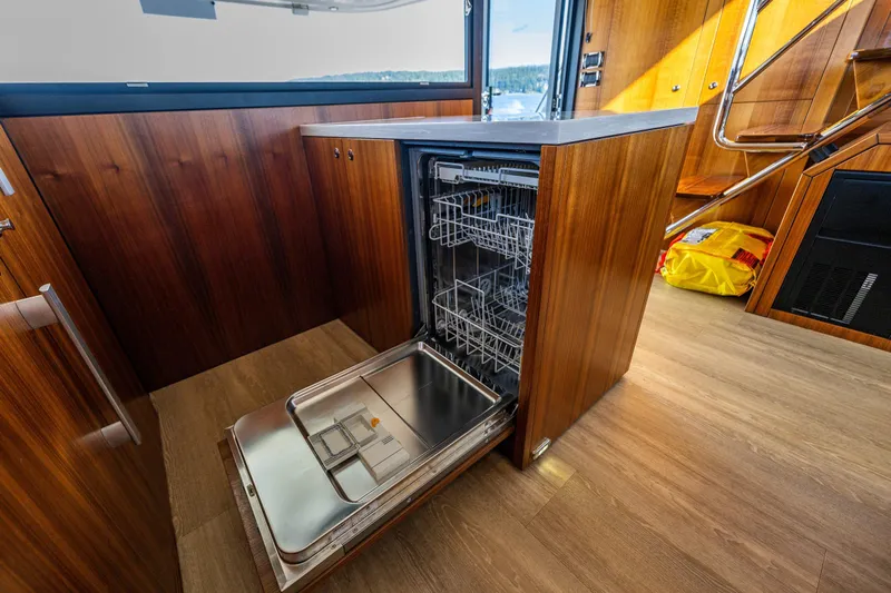True North Yacht Photos Pics 2020 Maritimo M59 yacht interior with open dishwasher, showcasing elegant wood finish.