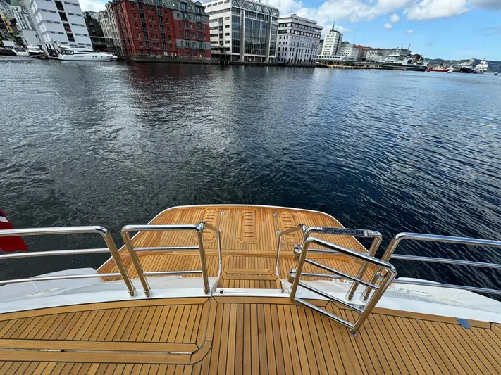  Yacht Photos Pics Rear view of 2009 Princess V65 yacht with wooden deck, overlooking waterfront cityscape.