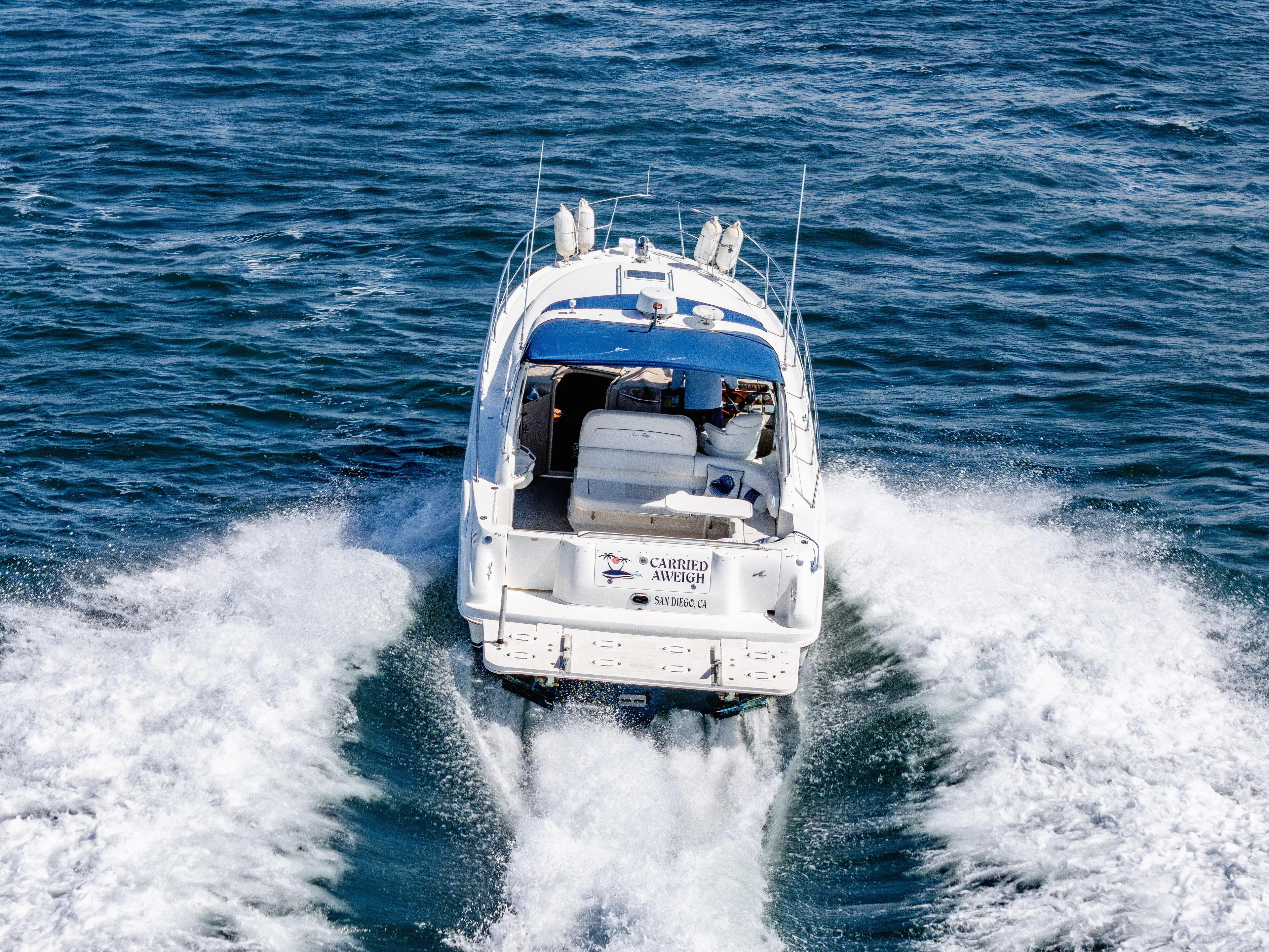"carried Aweigh" Yacht Photos Pics 1999 Sea Ray 400 Sundancer cruising on open water, rear view.