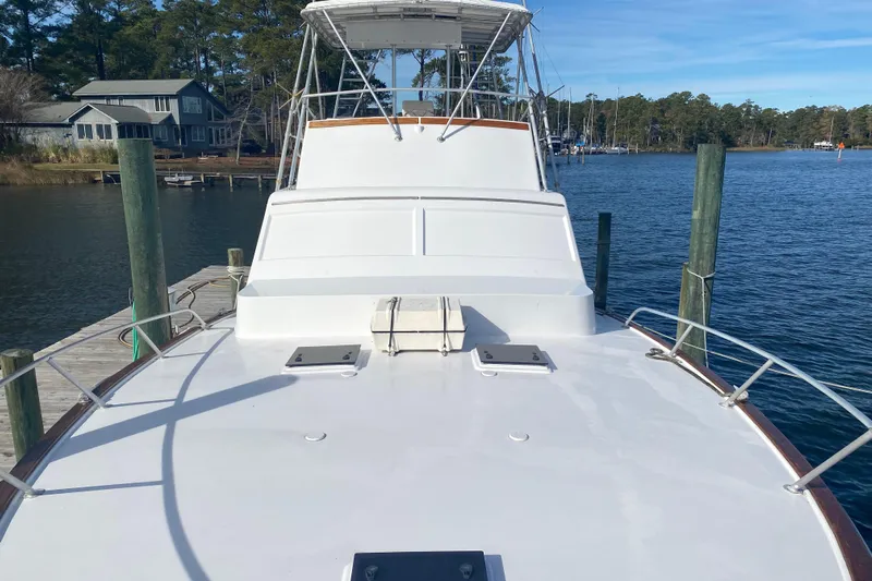 Second Chance Yacht Photos Pics 1986 Post 46 yacht docked by a serene waterfront with trees and houses.