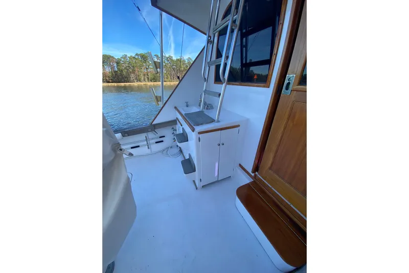 Second Chance Yacht Photos Pics 1986 Post 46 boat deck with sink, ladder, and wooden door by the water.
