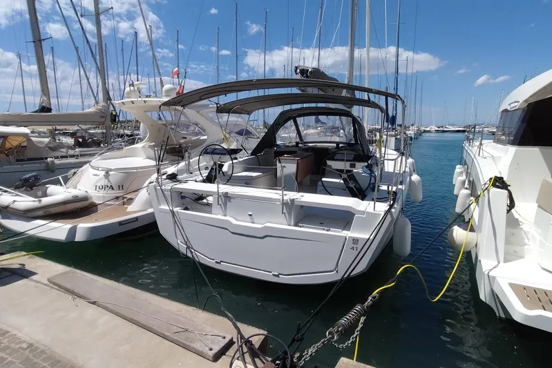  Yacht Photos Pics 2025 Dufour 41 yacht docked in a sunny marina, surrounded by other boats.