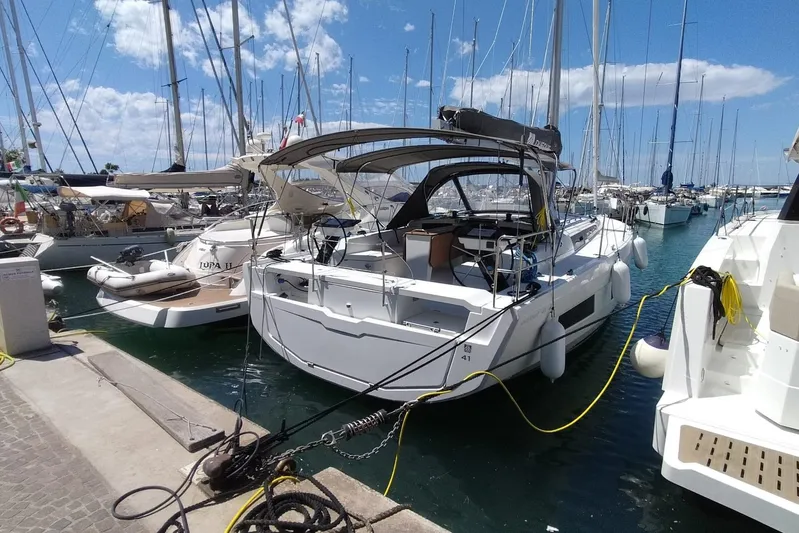  Yacht Photos Pics 2025 Dufour 41 yacht docked in a sunny marina, surrounded by other boats.