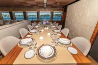 Luxurious yacht dining area with elegant table setting, featuring fine china and glassware, overlooking the ocean.