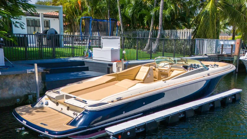 Levi Yacht Photos Pics 2013 Chris-Craft Launch 32 boat docked by a waterfront home with lush greenery.