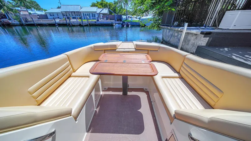 Levi Yacht Photos Pics 2013 Chris-Craft Launch 32 boat interior with beige seating and wooden table, docked by a serene waterfront.