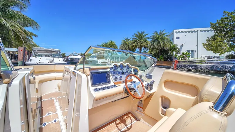 Levi Yacht Photos Pics 2013 Chris-Craft Launch 32 boat interior with steering wheel and dashboard, docked near palm trees.