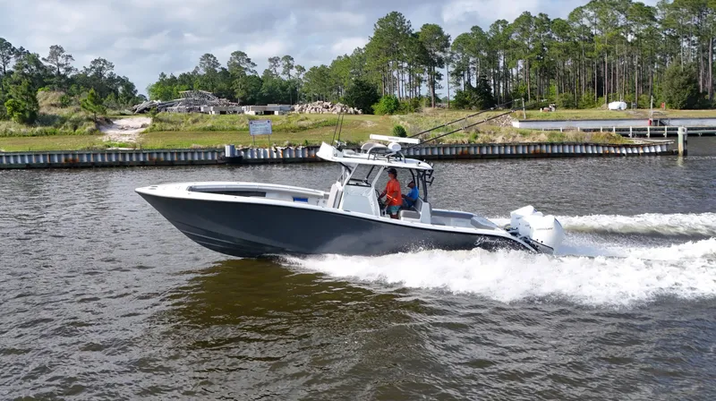 Engine Warranty X Trailer Yacht Photos Pics 2022 Yellowfin 34 boat cruising on a river with lush greenery in the background.