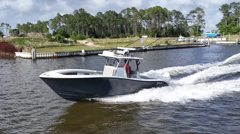 Engine Warranty X Trailer Yacht Photos Pics 2022 Yellowfin 34 boat cruising on a river with lush greenery in the background.