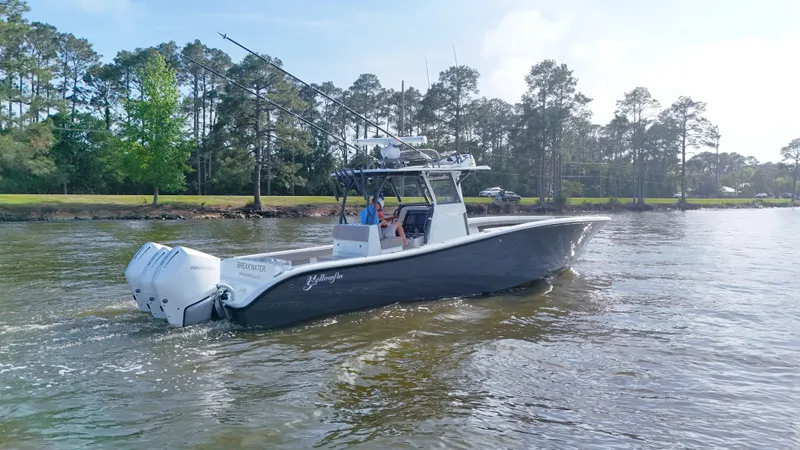 Engine Warranty X Trailer Yacht Photos Pics 2022 Yellowfin 34 boat cruising on a calm river with trees in the background.