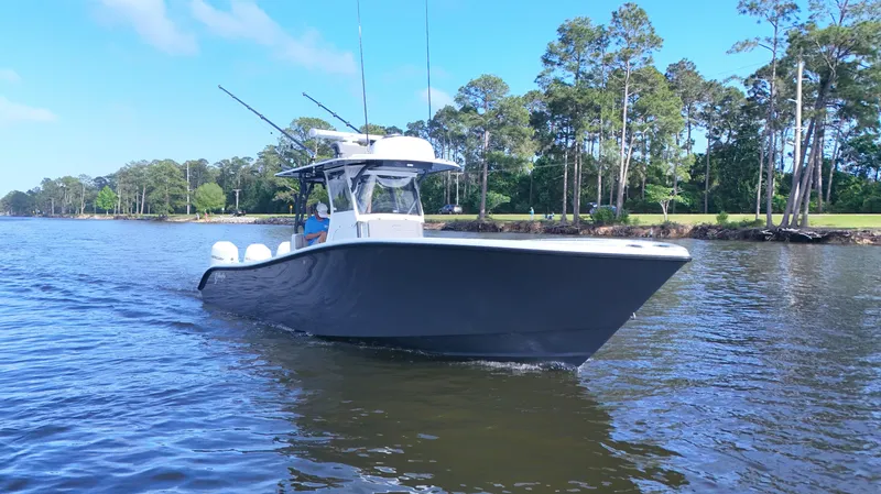 Engine Warranty X Trailer Yacht Photos Pics 2022 Yellowfin 34 boat cruising on a calm river with trees in the background.