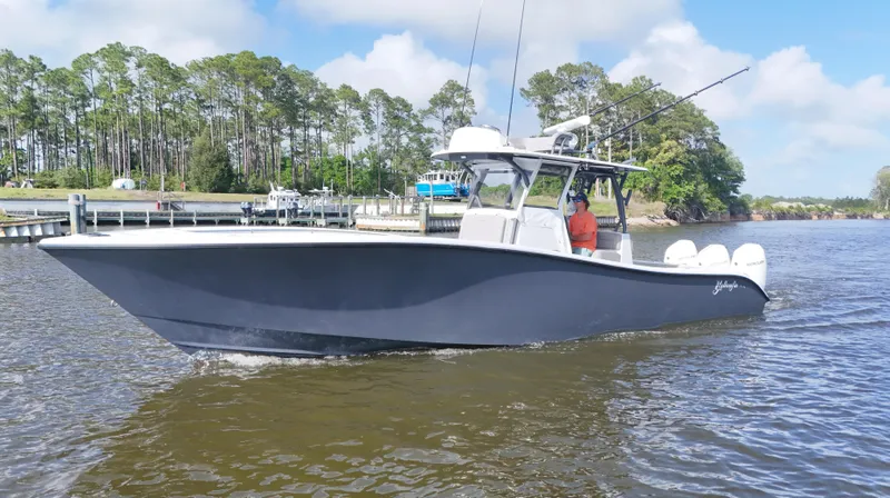 Engine Warranty X Trailer Yacht Photos Pics 2022 Yellowfin 34 boat cruising on a calm river with trees in the background.