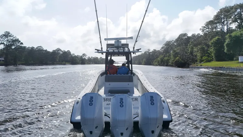 Engine Warranty X Trailer Yacht Photos Pics 2022 Yellowfin 34 boat cruising on a scenic river with triple outboard engines.